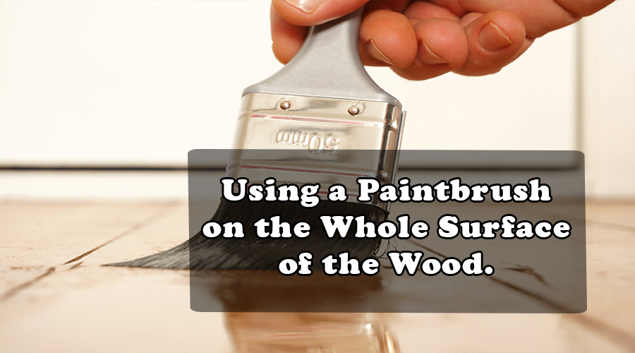 using a paintbrush on the whole surface of the wood