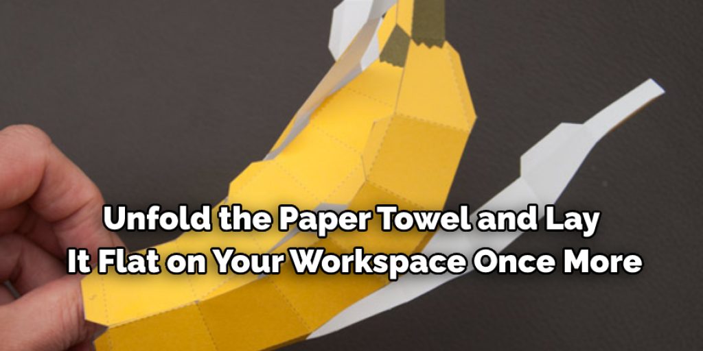 Unfold the paper towel and lay it flat on your workspace once more
