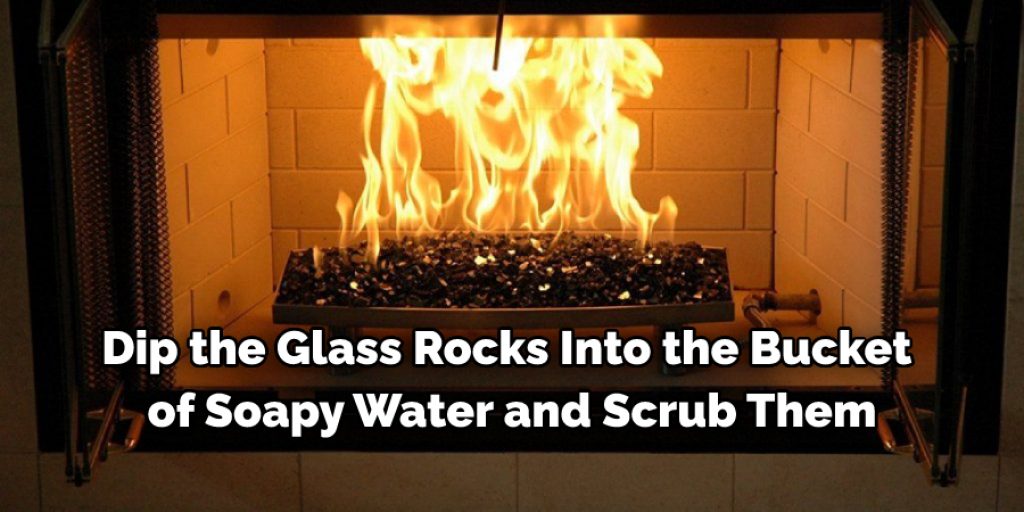 Dip the glass rocks into the bucket of soapy water and scrub them