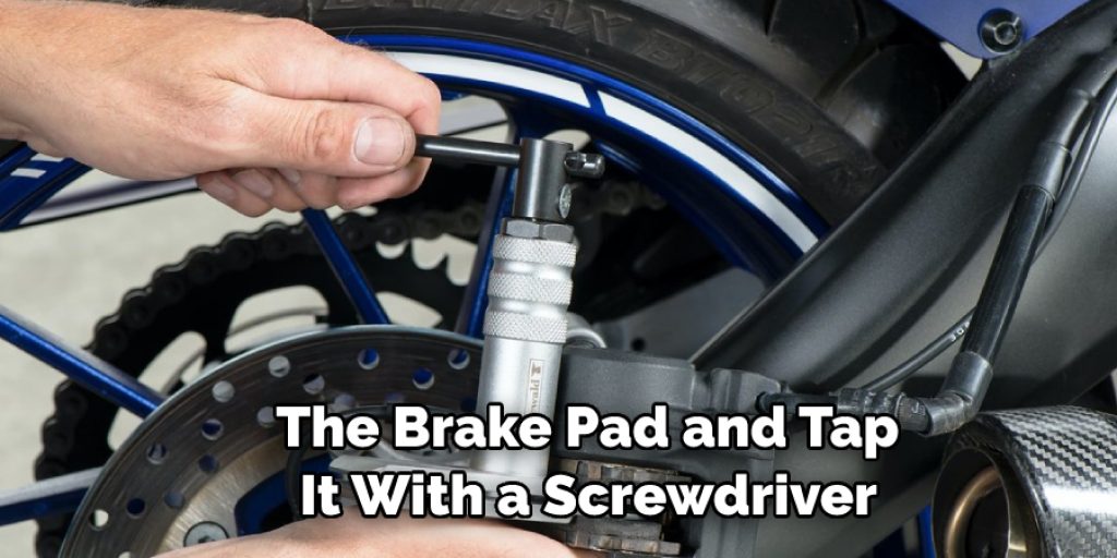  The Brake Pad and Tap  It With a Screwdriver
