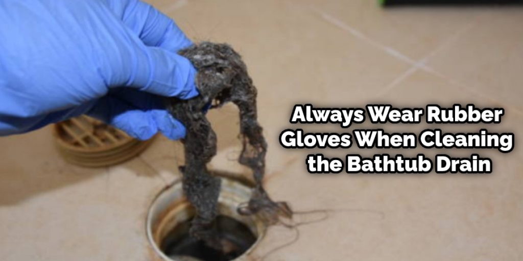Always wear rubber gloves when cleaning the bathtub drain. It prevents contamination from toxic substances and bacteria during the cleaning process.
